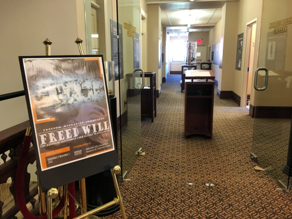 Photograph of the entrance to the Rollin Art Gallery. There is a sign outside of the gallery with a photograph from the exhibit, Freed Will: The Randolph People From Slavery to Settlement.