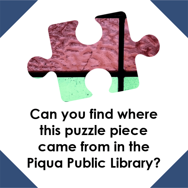 A graphic with a white background and navy blue corners. There is a puzzle piece with pink and sea green with black lines on it in the center. The black text under the puzzle piece reads "Can you find where this puzzle piece came from in the Piqua Public Library?"